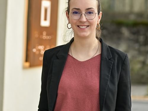 Femme élégante souriante devant une enseigne Hôtel Rivella.