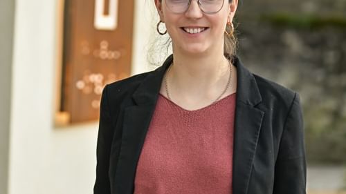 Femme élégante souriante devant une enseigne Hôtel Rivella.