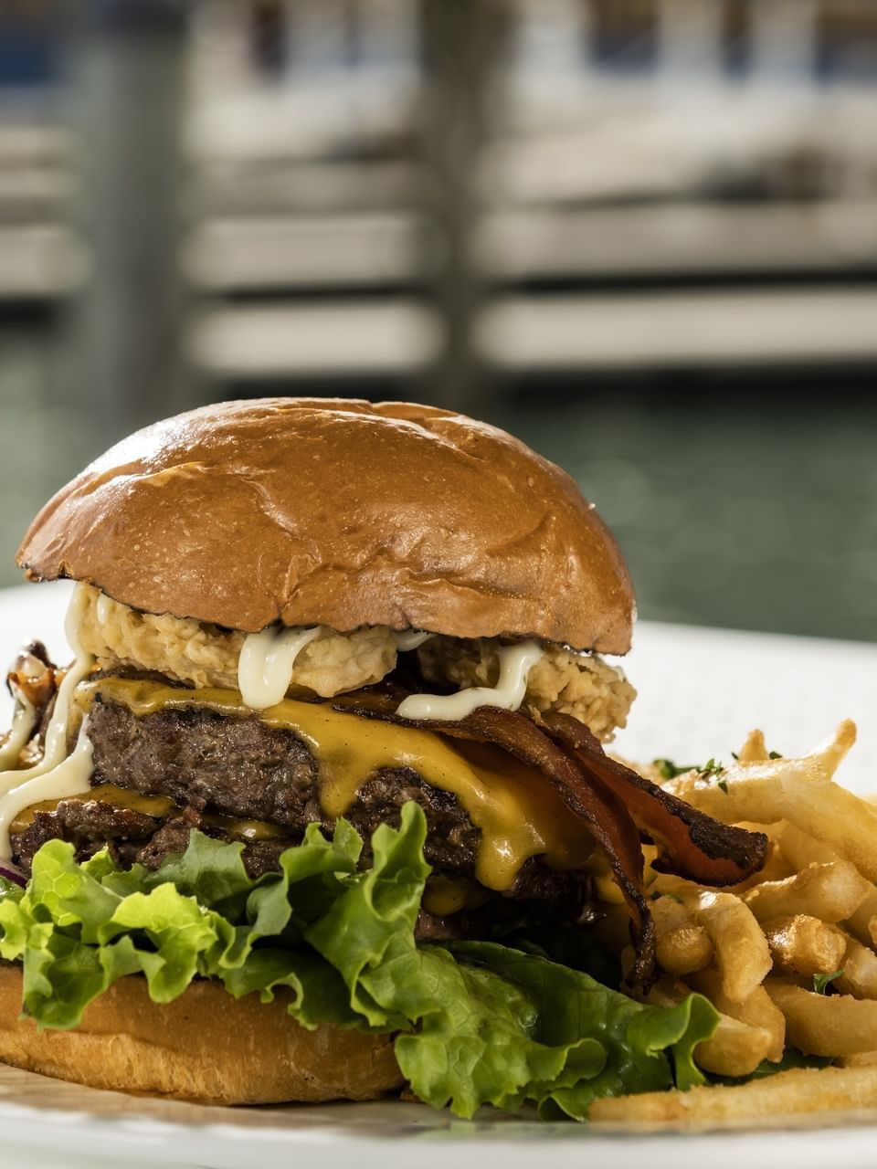 Hearty burger piled with cheese, bacon, lettuce, and mayo, served with a side of golden fries at El Conquistador Resort
