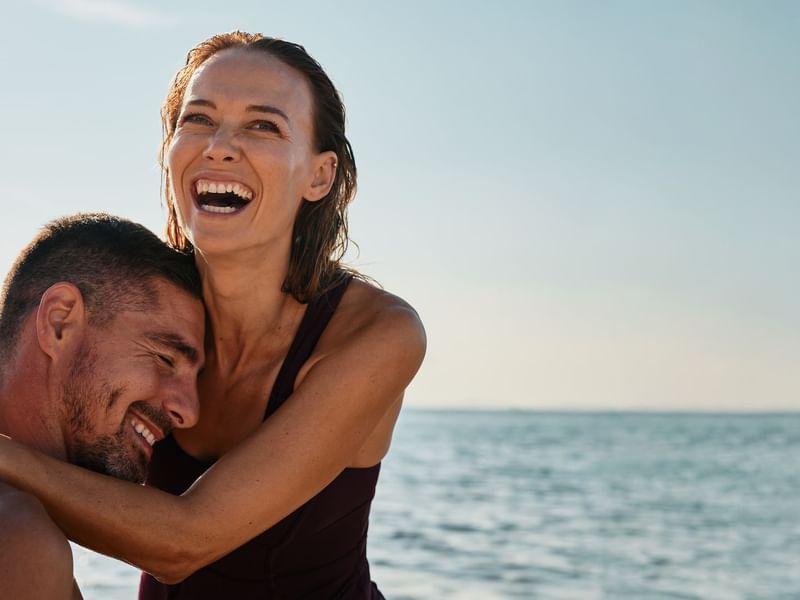 Two people embracing by the sea near Falkensteiner Luxury Villas