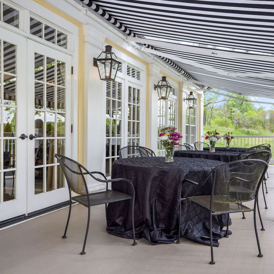 Outdoor patio with striped awning, tables with black cloths at the Inn at Willow Grove