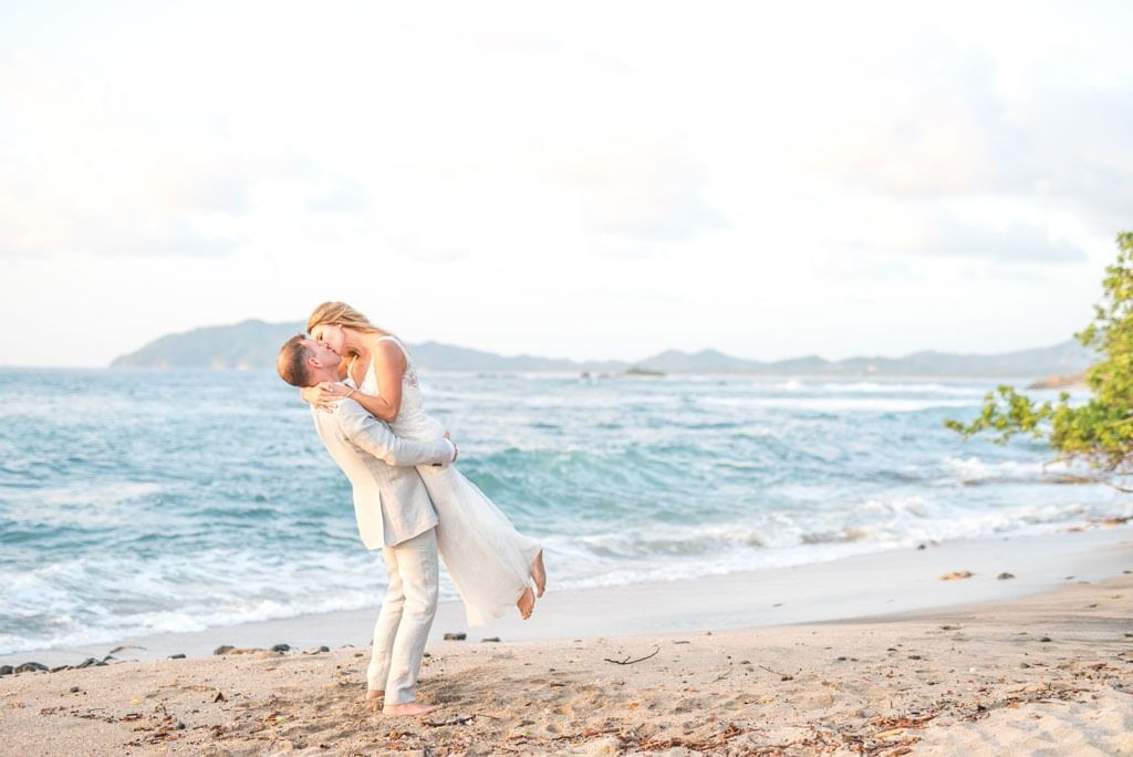 married couple kissing at the beach