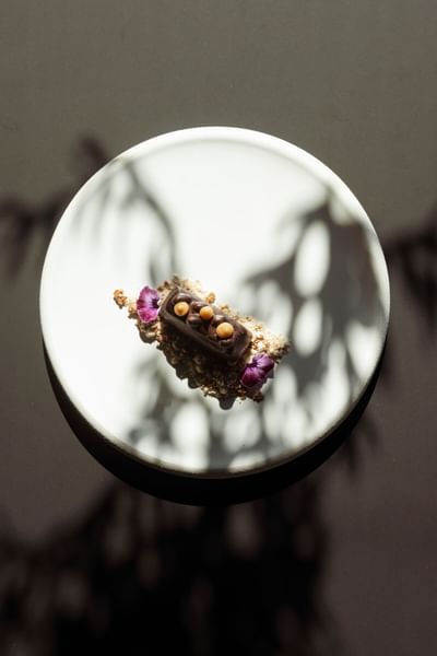 Dessert élégant avec des touches de chocolat et de fleurs sur un plateau blanc chez Grand Hotel Portovenere
