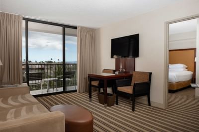 TV lounge with plush seating and a work desk by the window in Hoku Studio King Suite at Maui Coast Hotel