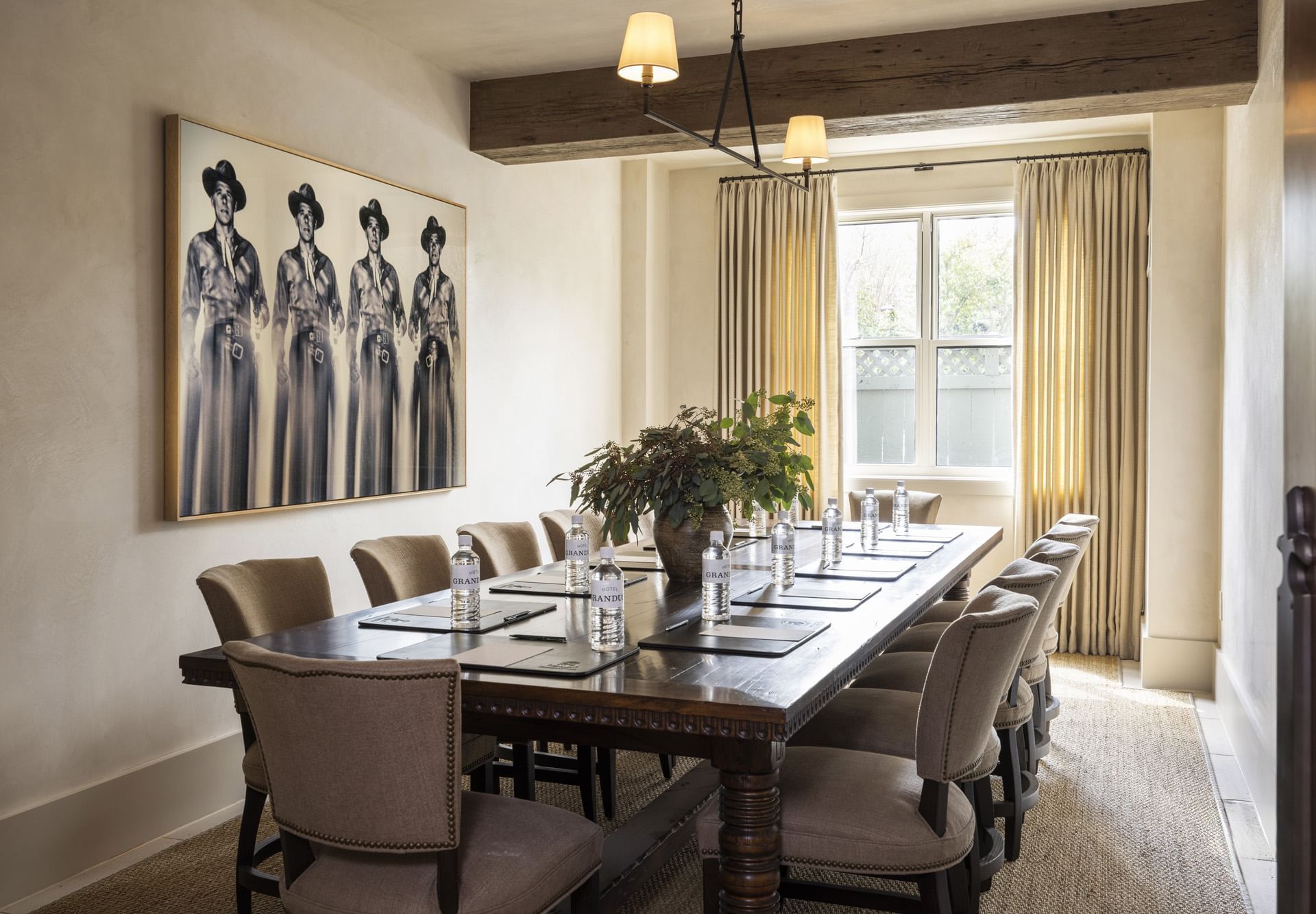 The Sweetspire Room at Granduca Houston with a long wooden table, cushioned chairs, and artwork on the wall