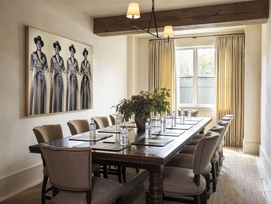 The Sweetspire Room at Granduca Houston with a long wooden table, cushioned chairs, and artwork on the wall