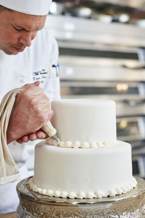 a chef adds icing to a cake