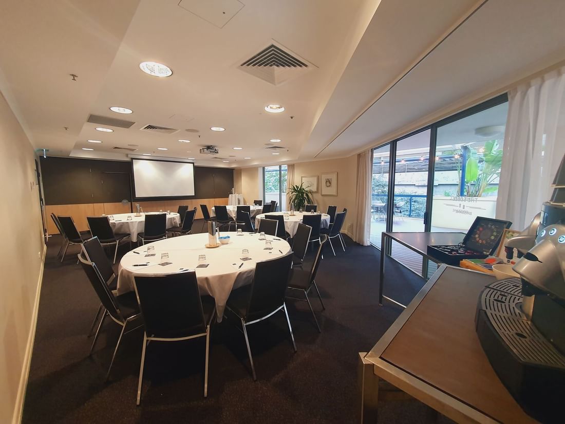 Albert I Room with round tables, a presentation screen, and a coffee station near the glass doors at The Sebel Brisbane