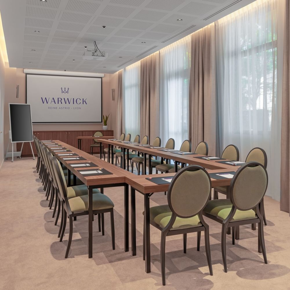 Salle de conférence moderne de Warwick Hotels and Resorts, équipée d'une longue table et de chaises pour une réunion d'entreprise