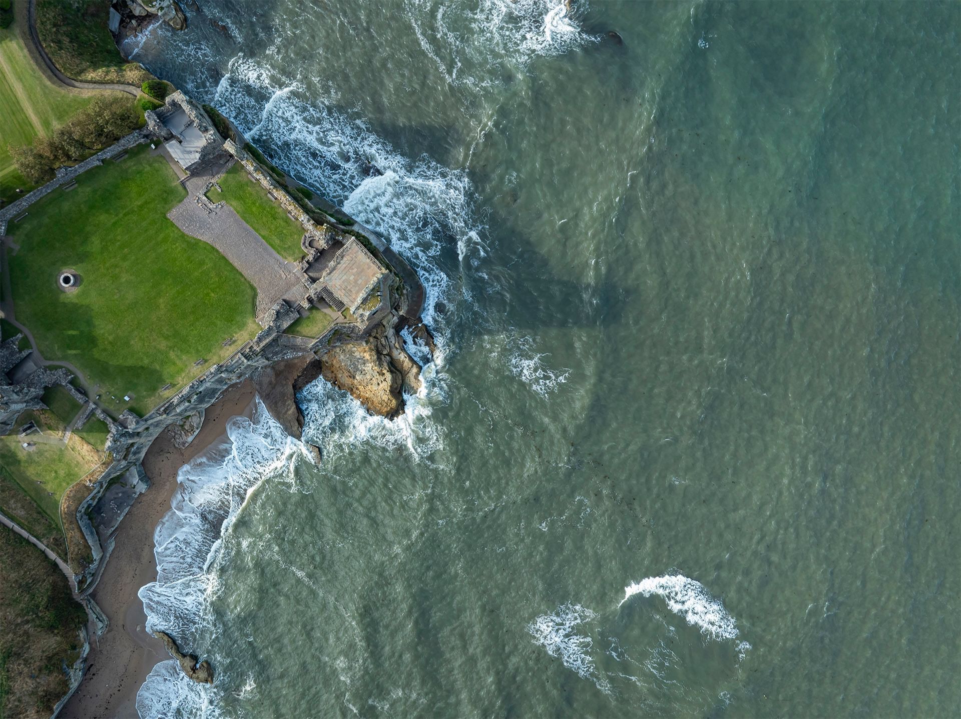 Aerial view of a rocky coastline waves crashing against the shore near hotels Fife scotland