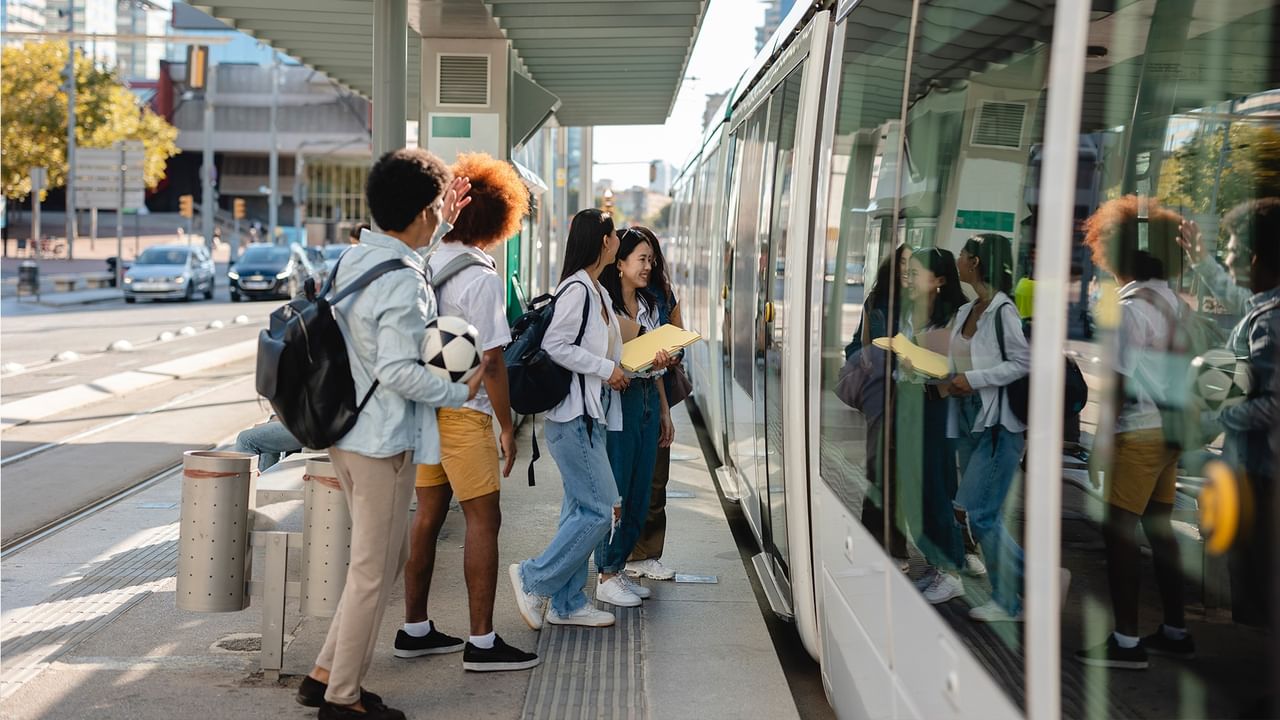People waiting at a modern light rail station with the East Link Light Rail arriving.