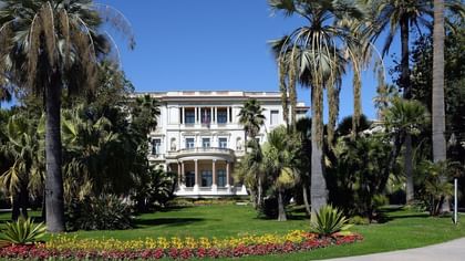 Beautiful historic architecture of Massena Museum surrounded by lush palm trees near Splendid Hotel & Spa Nice