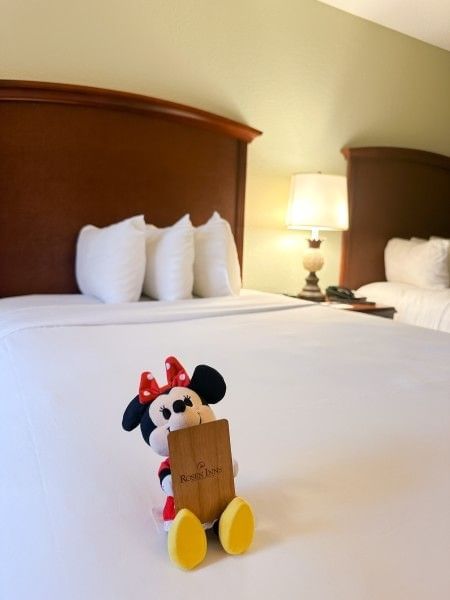 A plush Minnie Mouse toy holding a key card to a hotel room at Rosen Inn Lake Buena Vista, a family-friendly hotel in Orlando.