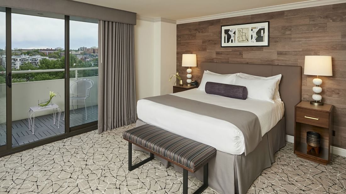 Comfy bed with side tables and balcony in Deluxe Room at Warwick Denver