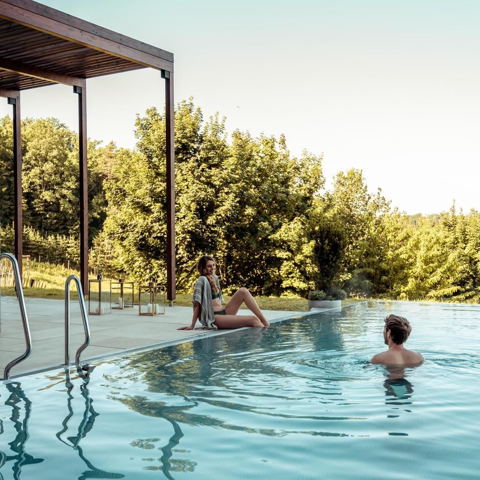 A couple enjoying the outdoor pool at Falkensteiner Hotels