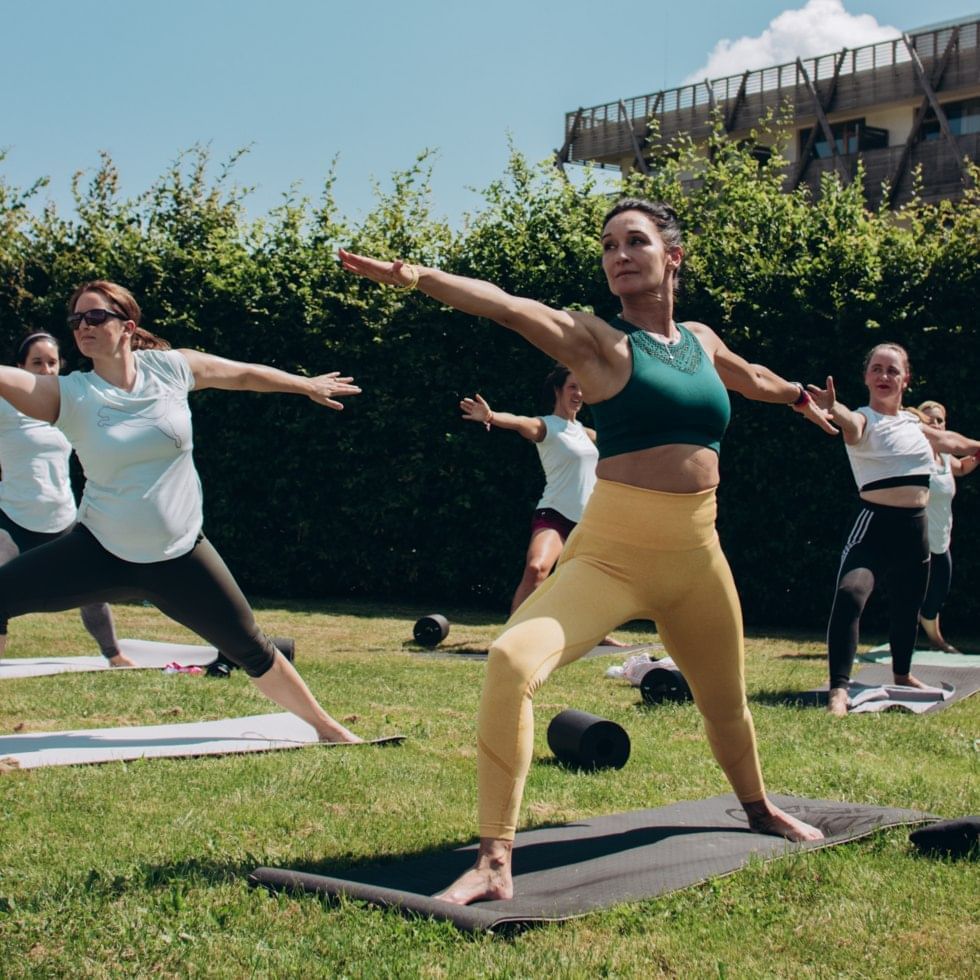 Group of people practicing yoga on mats outdoors at Falkensteiner Genuss & Wohlfühlhotel Mühlviertel