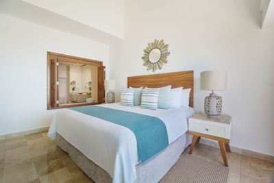 A bright luxury hotel suite bedroom featuring a king-size bed with elegant turquoise accents.