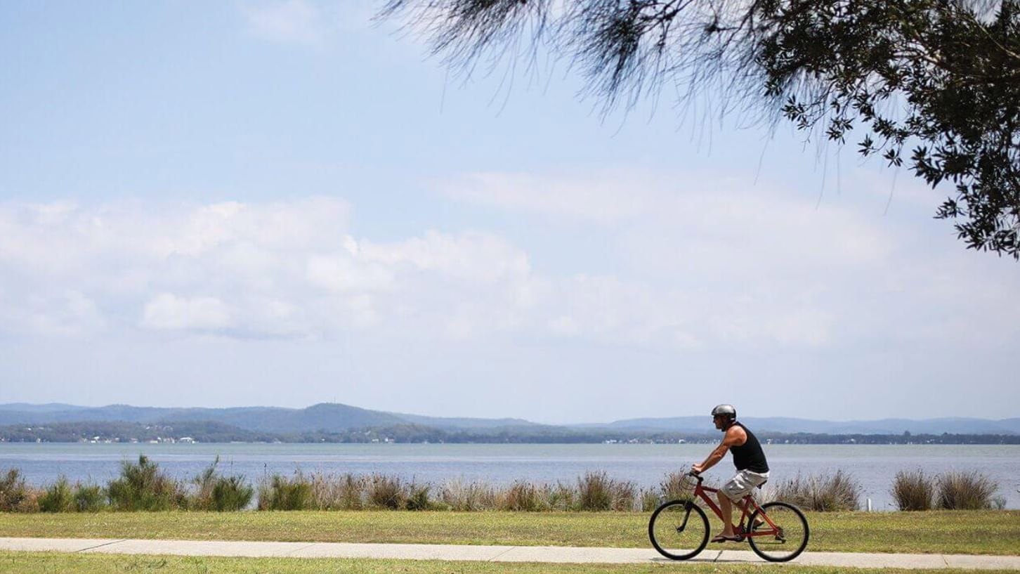 Man cycling round the Tuggerah Lakes Cycleway near Pullman Magenta Shores