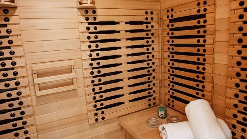 White towels on a wooden bench by a sauna wall featuring black infrared heaters at Cantonal Hotel by Warwick Riyadh