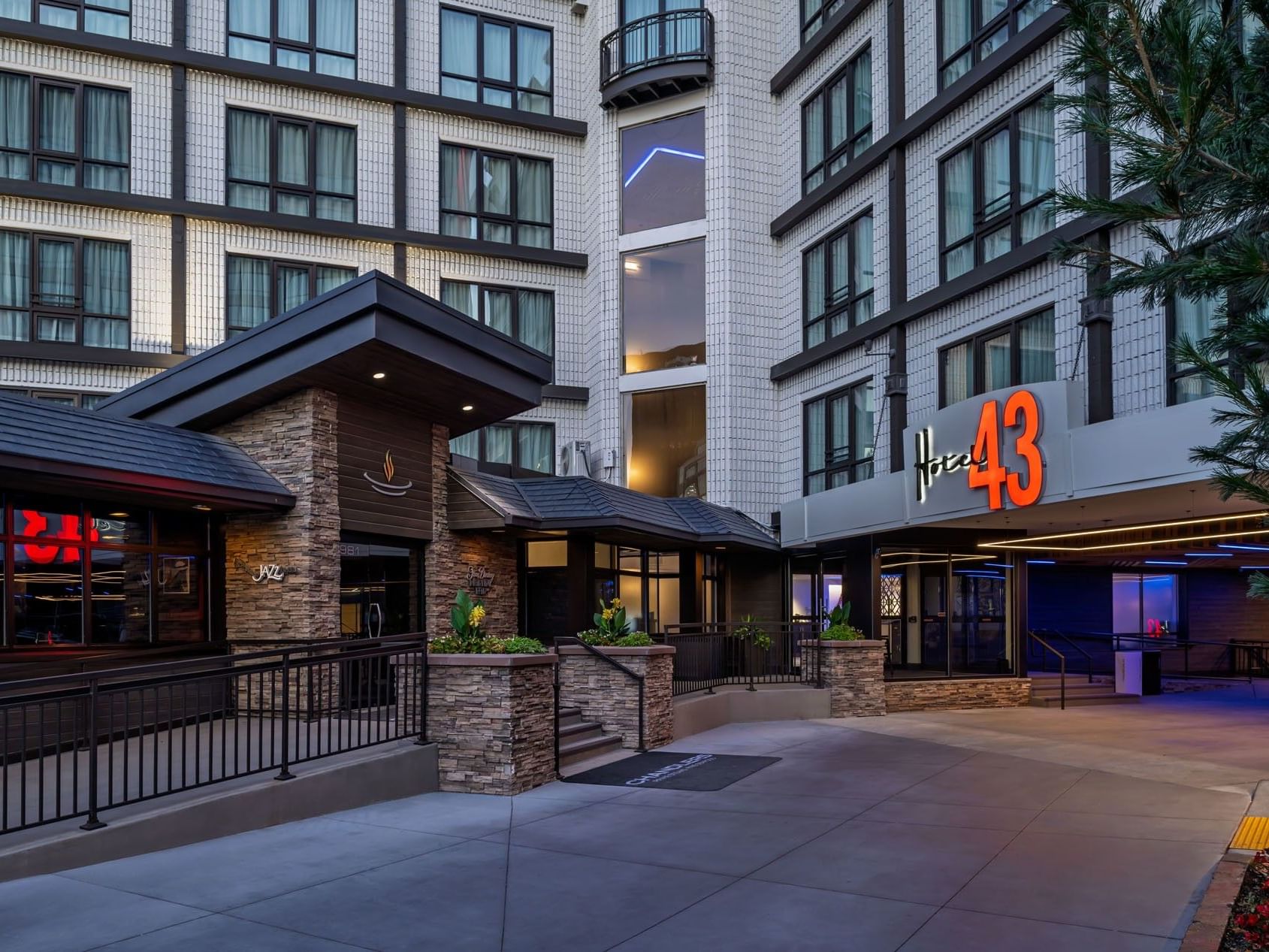 The main entrance of Hotel 43 Boise with its modern stone facade and the brightly lit Hotel 43 sign