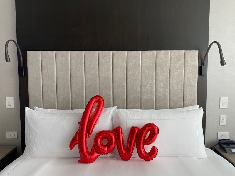 Love balloon on a bed with white pillows in a room featuring Hotel X Toronto deals