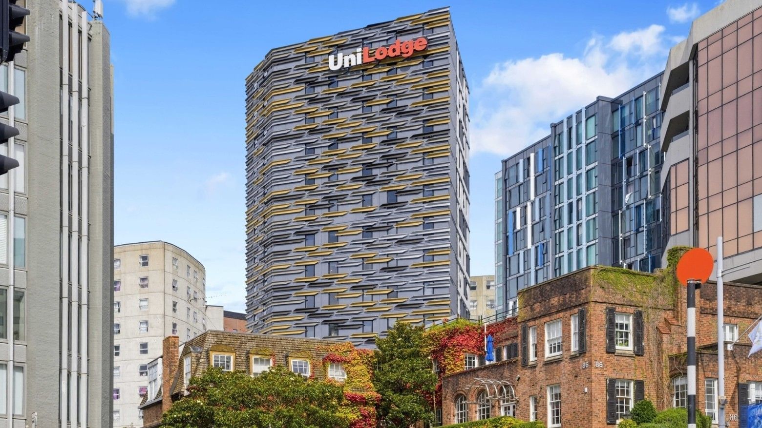 UniLodge building with unique facade design standing tall among other city buildings.