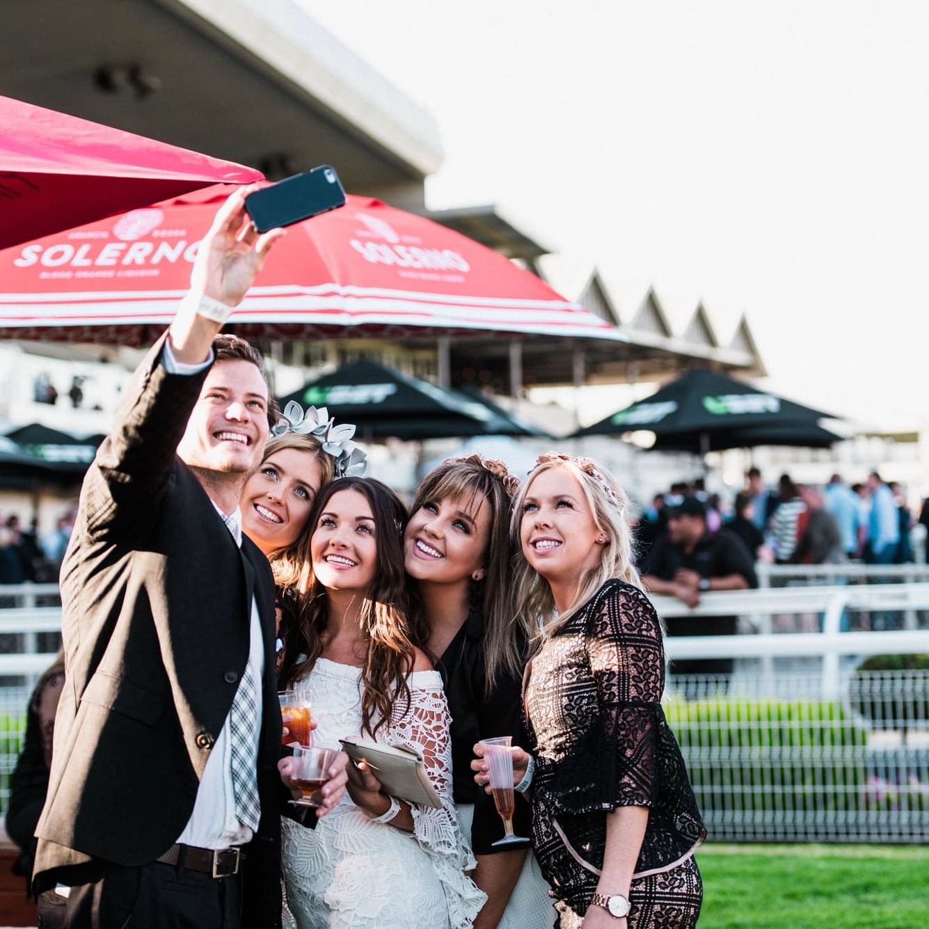 Four people taking a selfie under umbrellas at the Adelaide Cup.