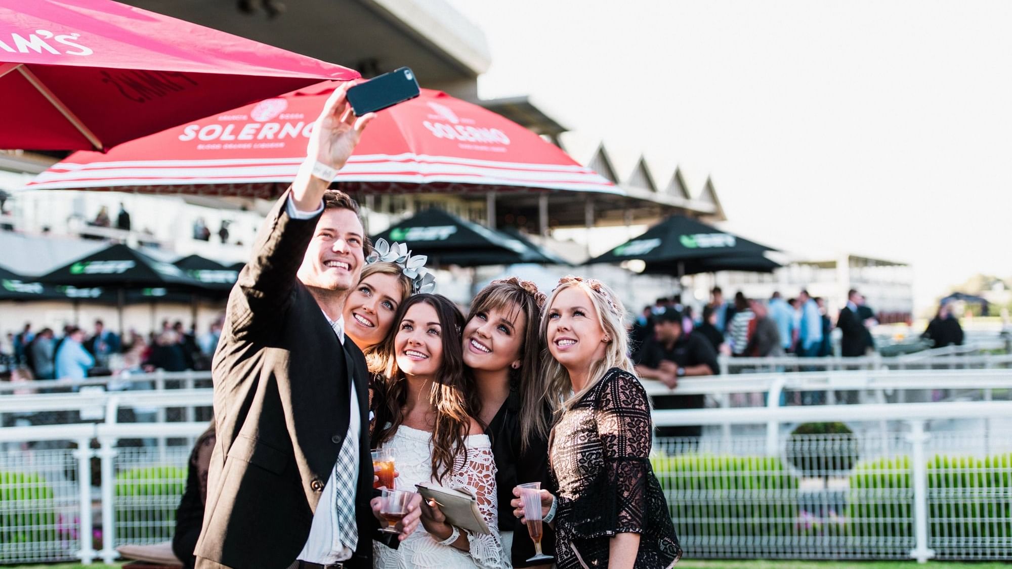 Four people taking a selfie under umbrellas at the Adelaide Cup.