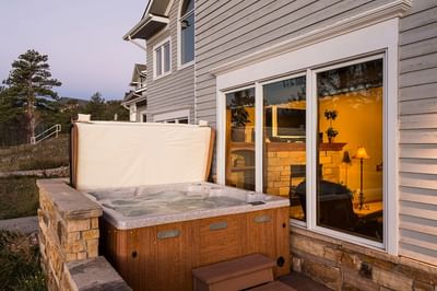 A bubbling hot tub on a patio next to a house at The Stanley Hotel, with a large window next to it