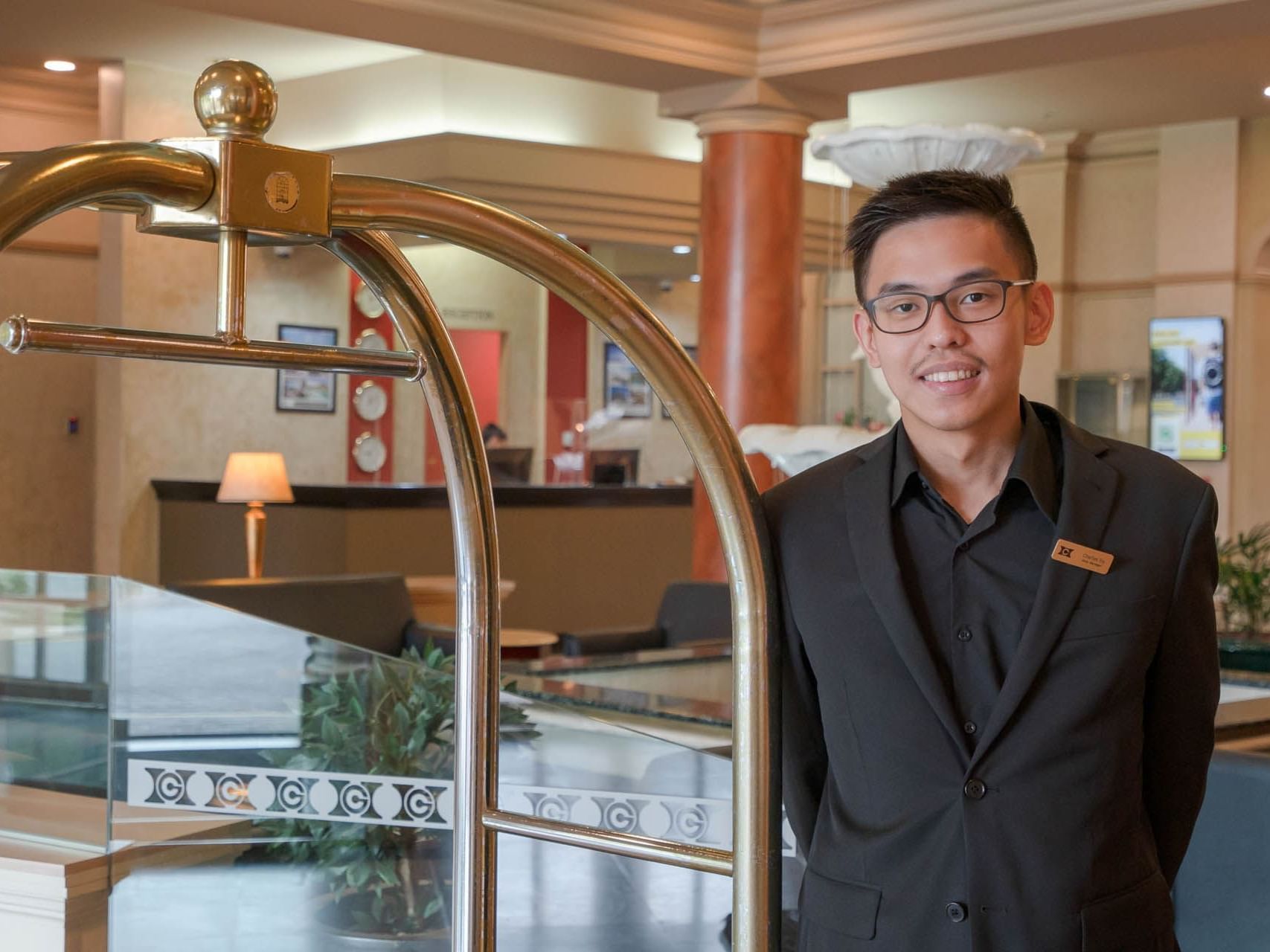 Receptionist standing by a luggage trolley in the lobby at Grand Chancellor Launceston