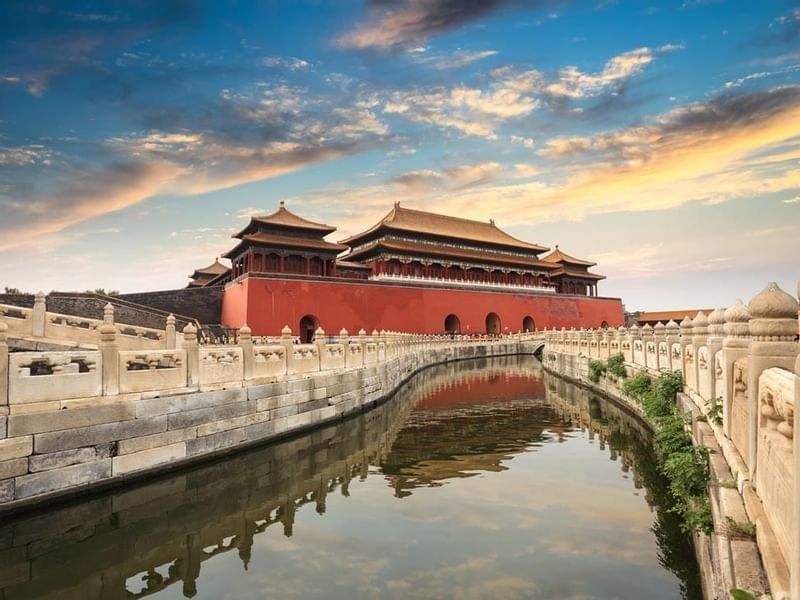 Golden hour over the Forbidden City with a stone bridge crossing a canal near Celebrity International Grand Hotel