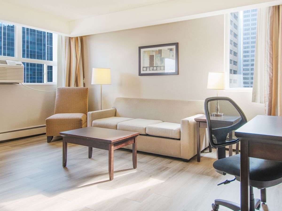 Hotel suite living area with work desk, chair, sofa, and table
