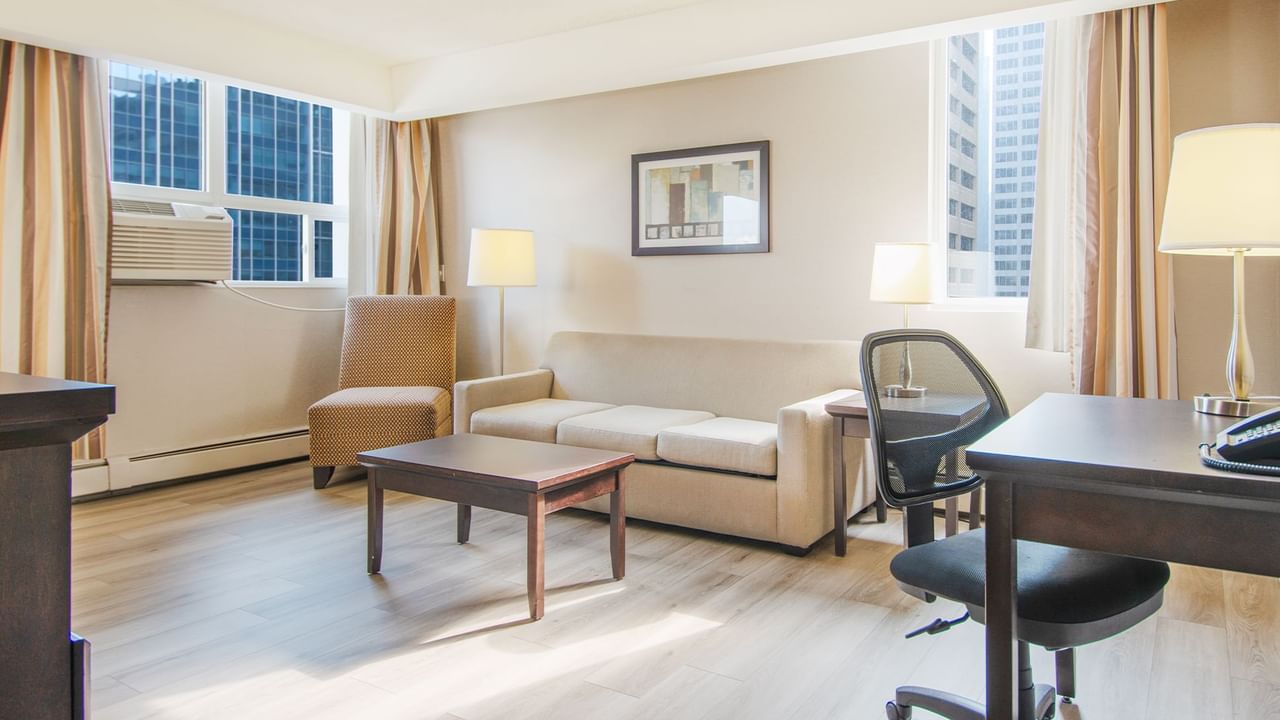 Hotel suite living area with work desk, chair, sofa, and table
