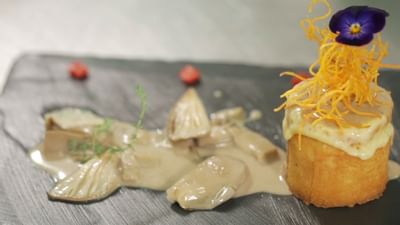 Arranged food with a blue flower on top at Hotel Sumaq