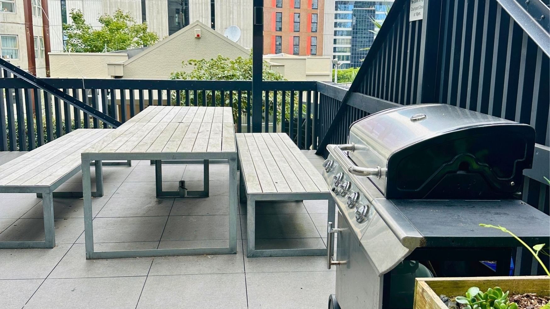 Outdoor seating with table, benches, and grill at UniLodge Auckland City.