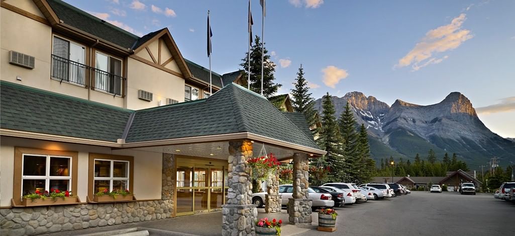 A hotel in Canmore with the mountains in the background on a sunny summer day.