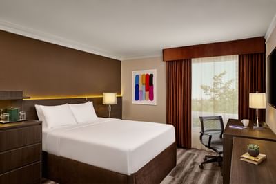 Guest room with bed, desk, chair, window, and modern decor.