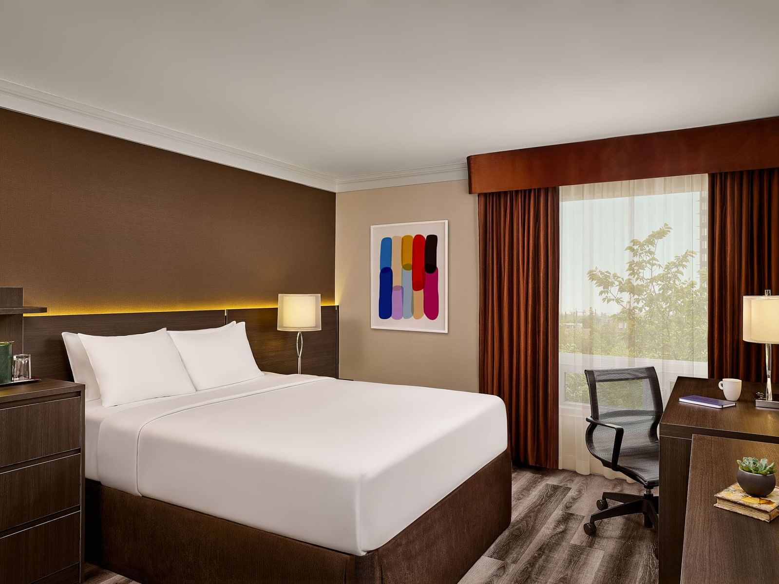 Reimagined Deluxe Queen with a king bed, modern art, and dark wood furniture at the Varscona Hotel on Whyte