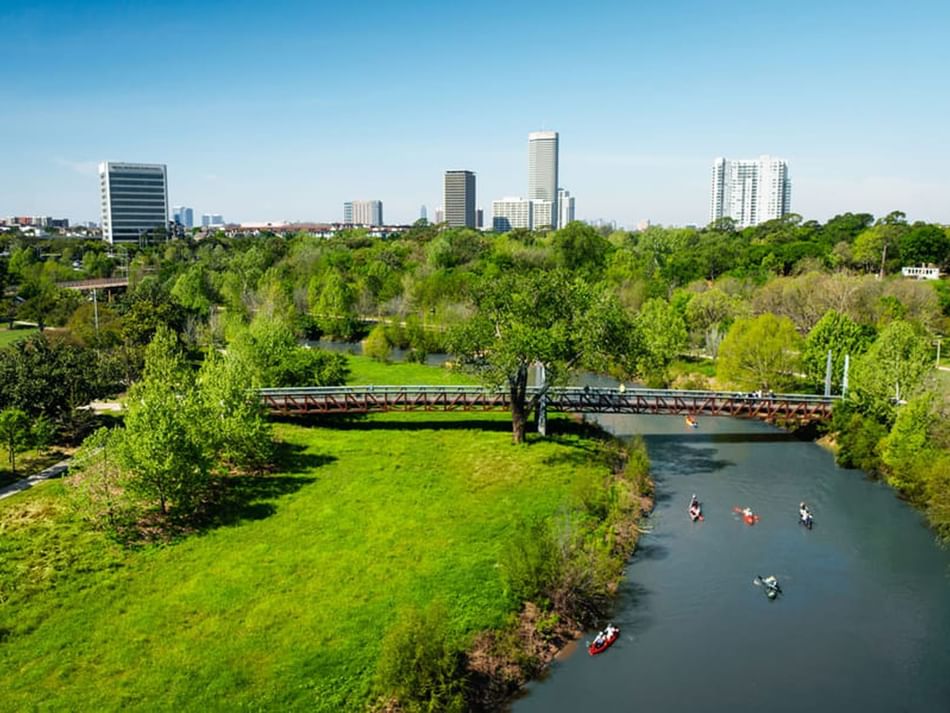 Buffalo Bayou Park near Granduca Houston with kayakers, greenery, and skyline views by Uptown Park Houston