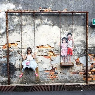A penang mural of brother & sister on a swing