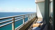 Oceanfront guest room with floor-to-ceiling windows and private balcony.