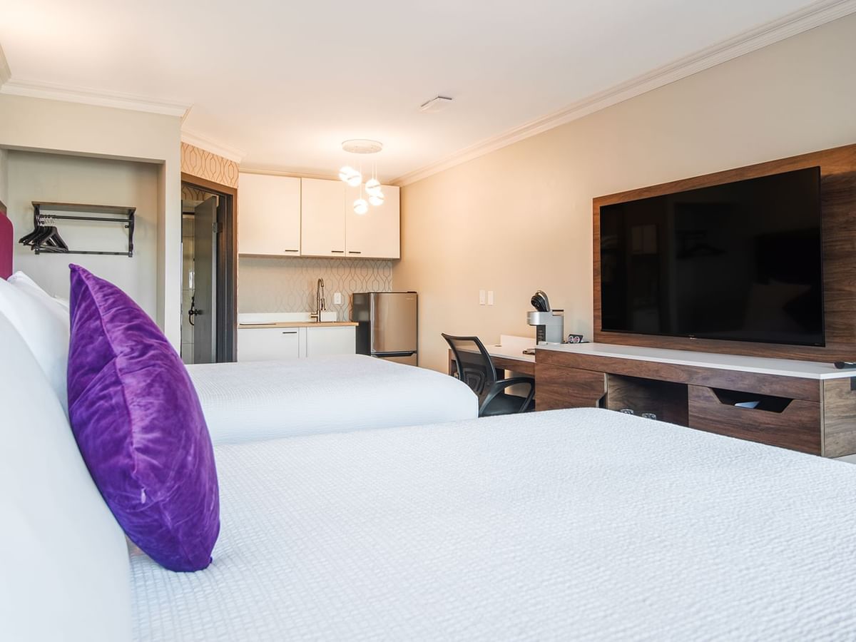 Hotel gust room with two queen beds, flat screen TV, kitchenette, and work desk