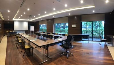 Aquamarin room at The Saujana Hotel Kuala Lumpur with long tables, a projector, and garden views through large windows