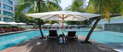 Pool area with sun beds under a canopy at MiCasa All Suite Hotel KL