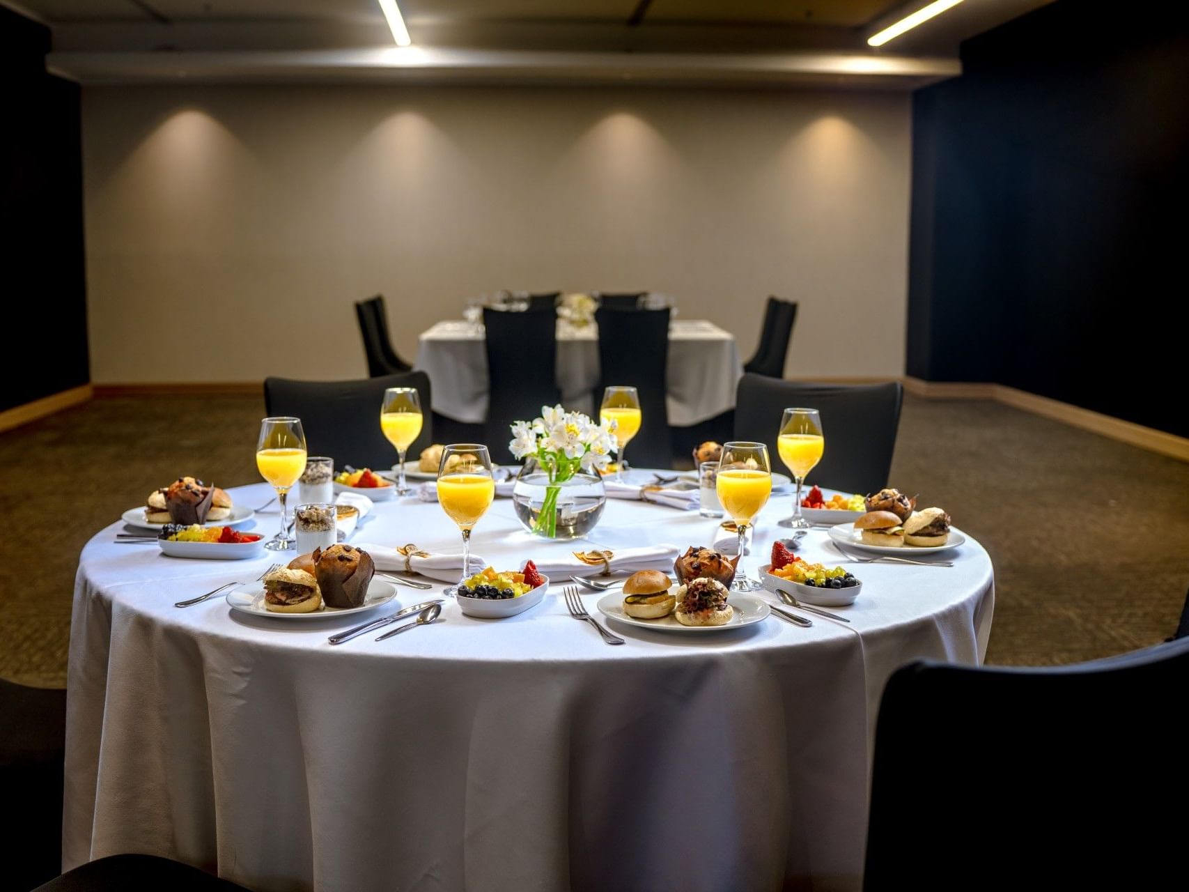 Una mesa redonda preparada para el desayuno con comida, bebidas y cubiertos en el hotel HCC Costanera Concepción.