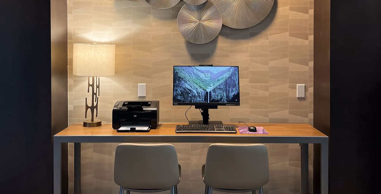 Office Centre of a hotel with chair, table, lamp. computer, and printer