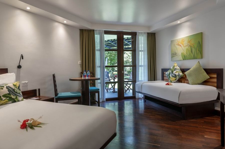 Garden View Rooms feature two beds, a round table with chairs by glass doors at Warwick Fiji Resort and Spa