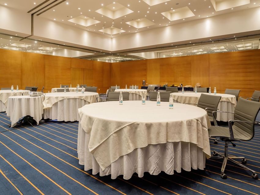 Monaco event room tables with white cloths and bottled water in the spacious conference room at Real Inn Torreon