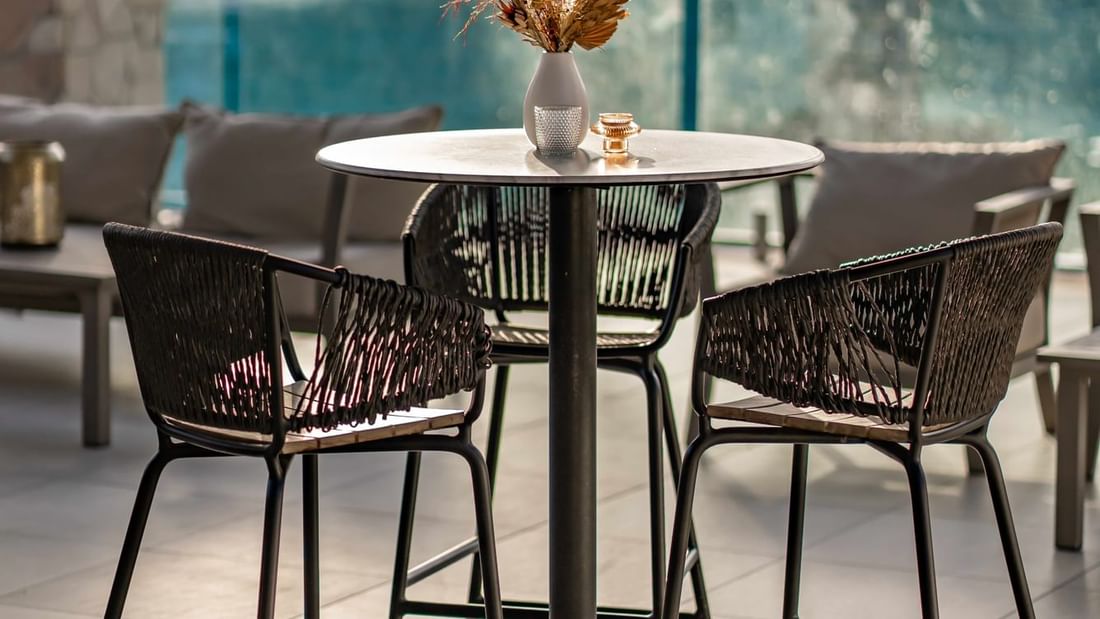 Elegant outdoor setting with wicker chairs and marble table with vase in Lagoon View Terrace at Pullman Port Douglas