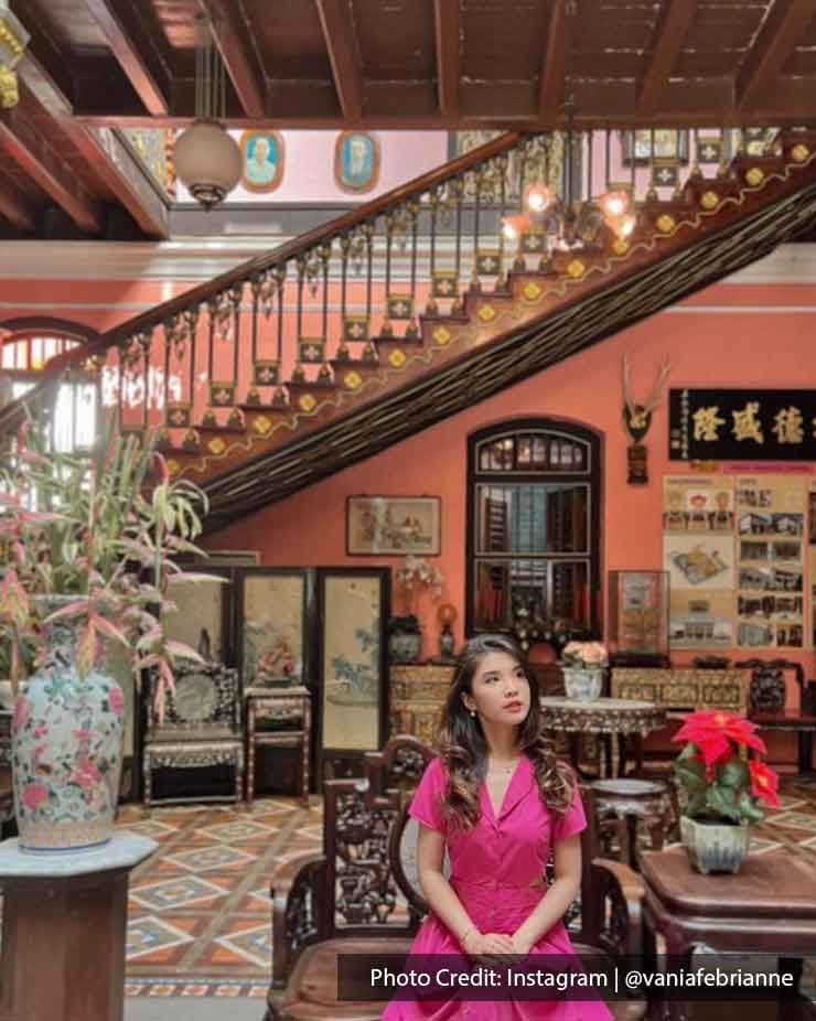 A woman dressed in a pink dress sat on a chair inside the Pinang Peranakan Mansion - Lexis Suites Penang
